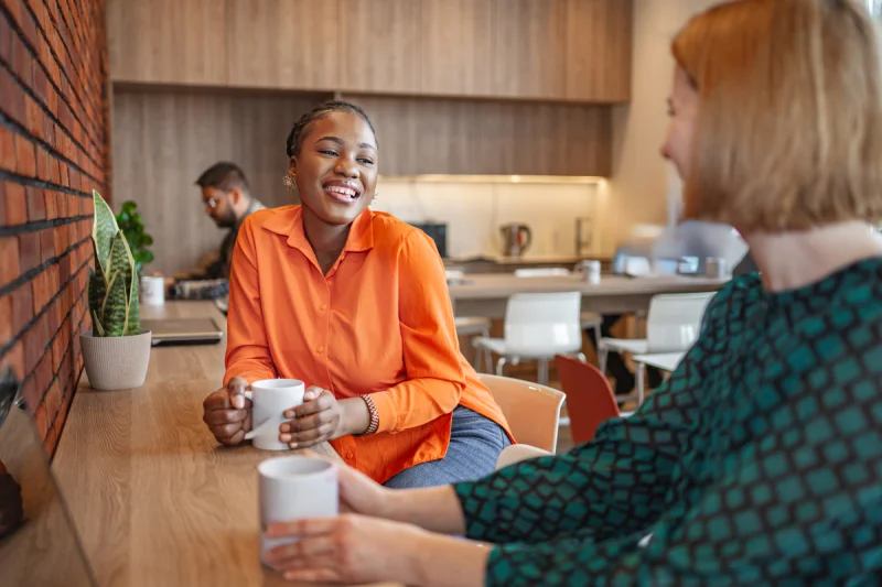 Two colleagues sharing coffee and conversation, representing a donor cultivation meeting