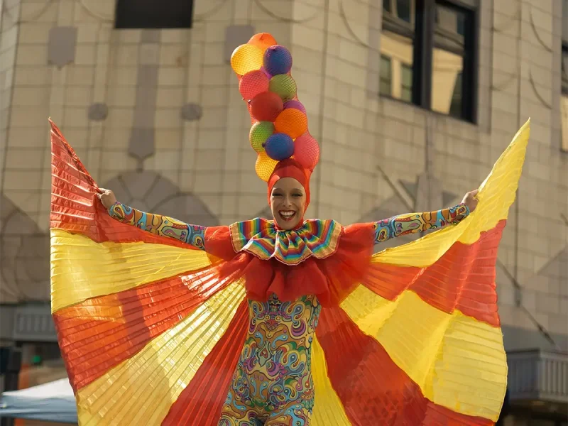 A parade performer wearing a hat of balloons